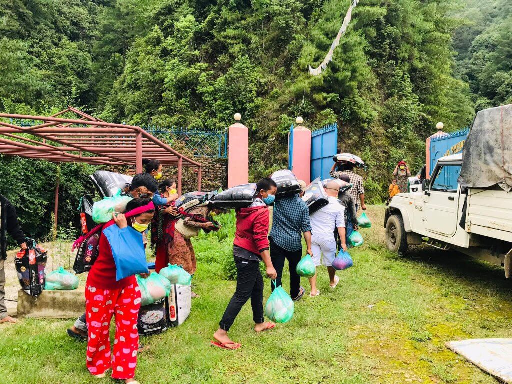 Local parents wearing masks carry sacks from a truck parked in the school grounds.
